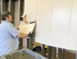 A worker takes off sheetrock from the wall separating the cardio and weight rooms.